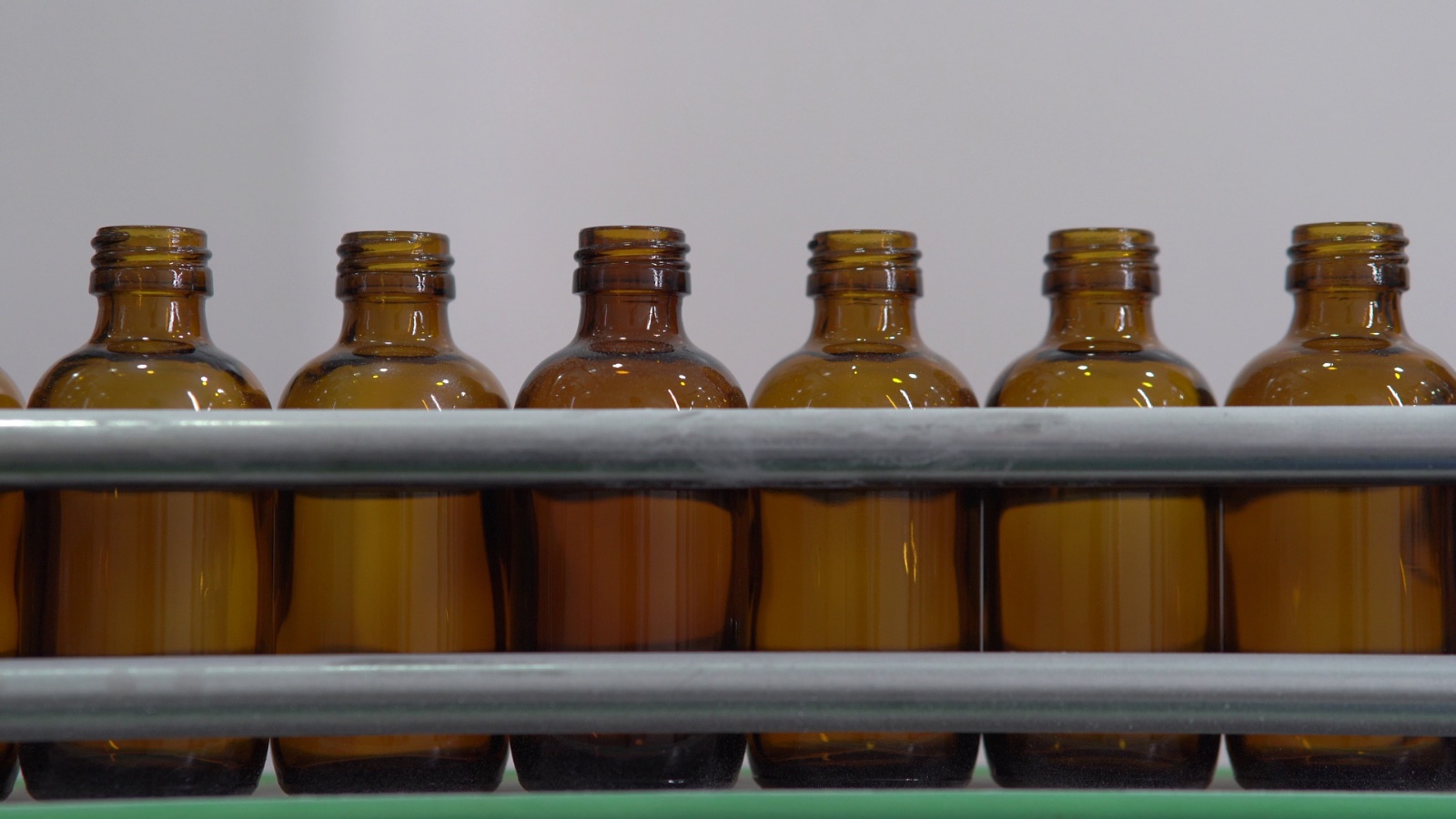 Row of amber glass bottles on a filling line