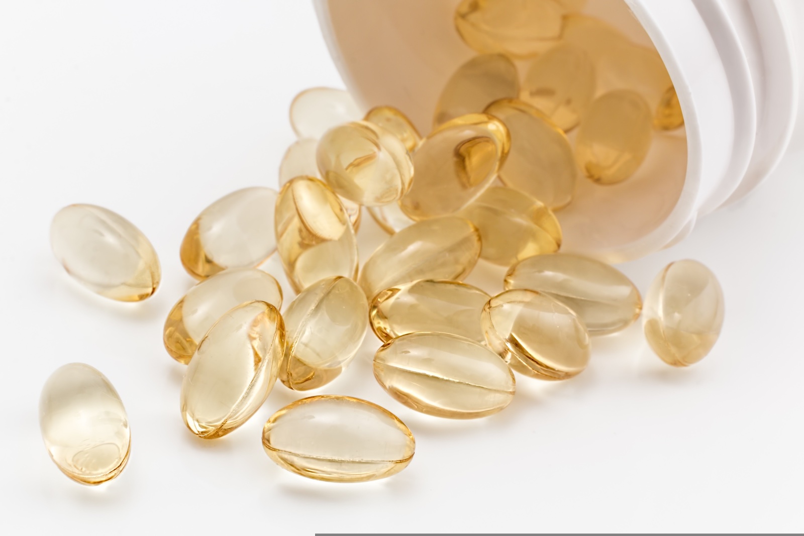 Golden softgel capsules spilling from a bottle