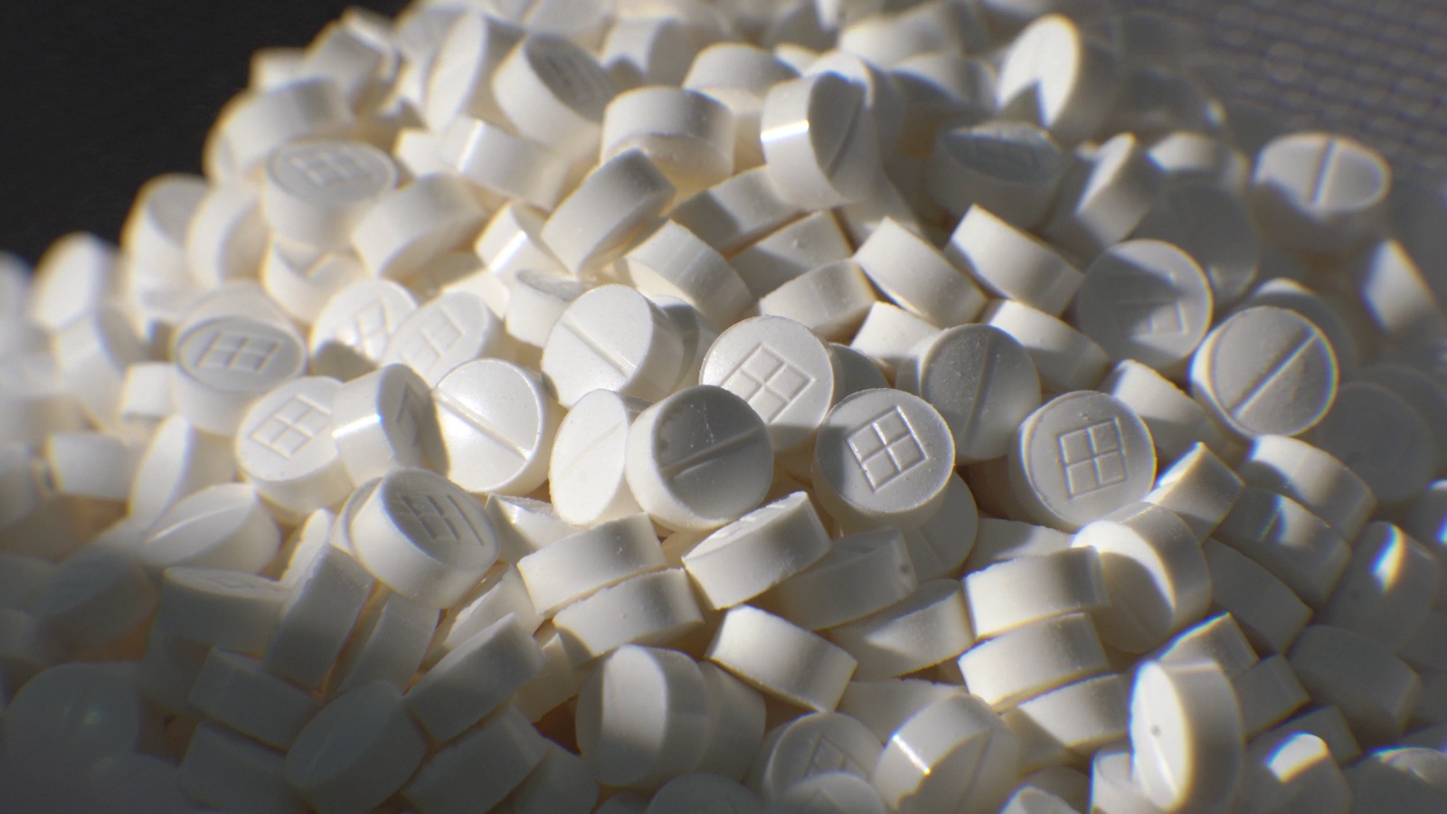 Close-up of white round tablets embossed with a square mark