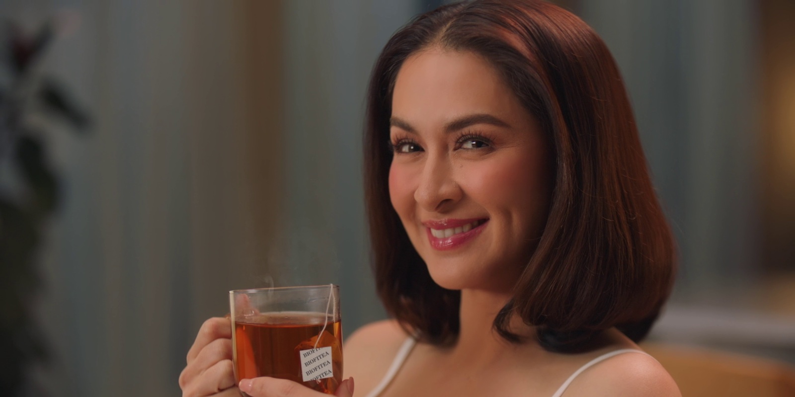 Woman smiling while holding a warm cup of herbal tea